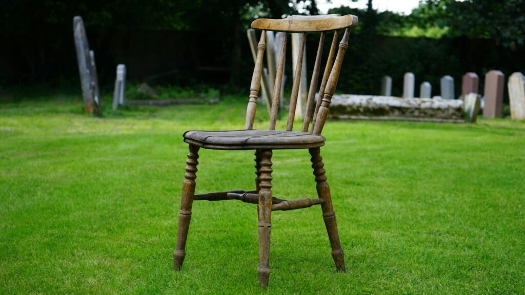 A vintage wooden chair sits alone in a serene cemetery 