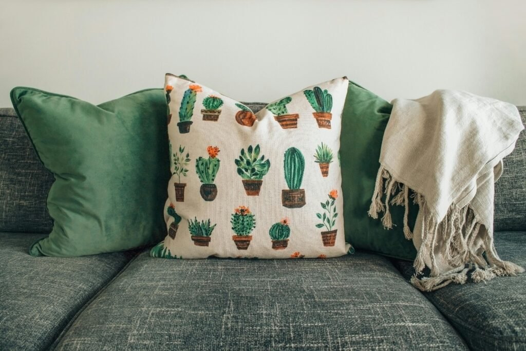  modern living room sofa with green cushions, cactus pillow, and cozy throw blanket