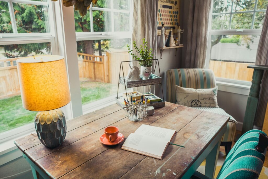 home office setup featuring a vintage wooden desk, a warm lamp, and homey decor.