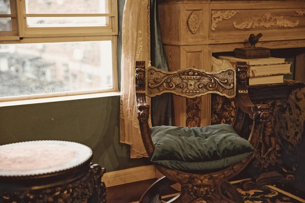Luxury vintage wooden chair beside a window with books and decor.