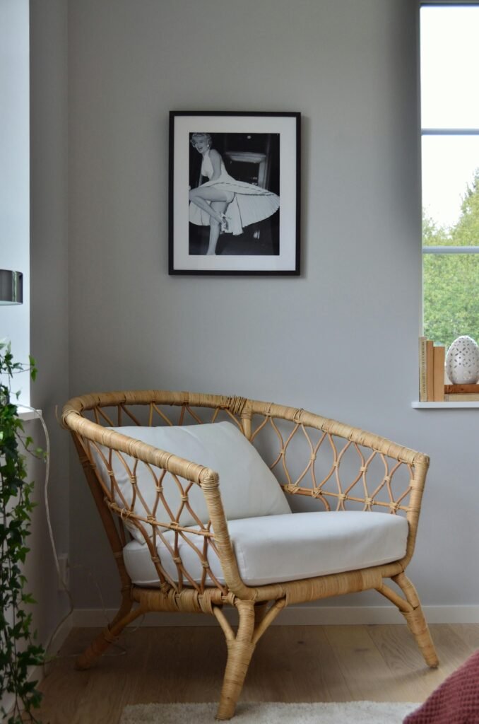 A stylish rattan chair in a Scandinavian-designed room with a framed photo on the wall.