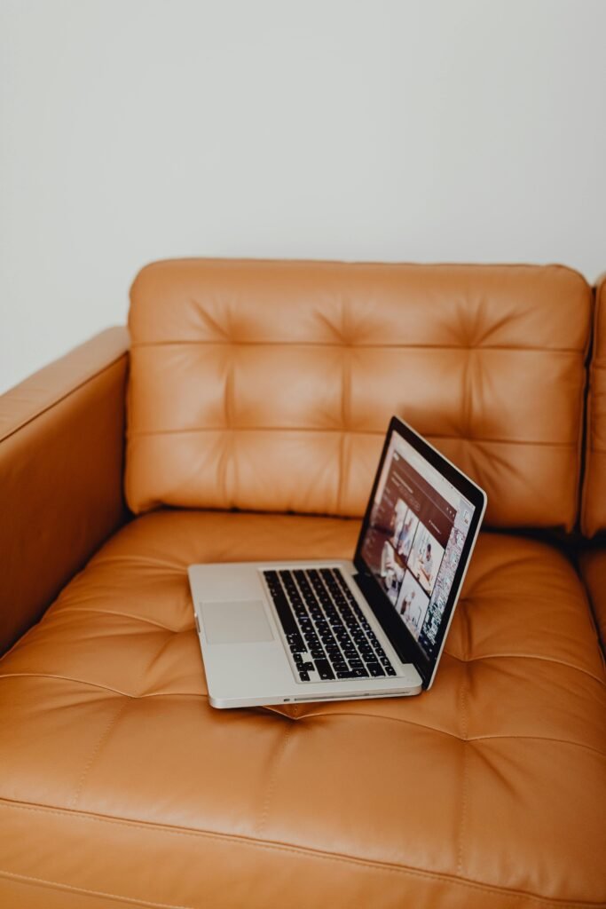 A sleek laptop rests on a luxurious tan leather couch, embodying a modern lifestyle.