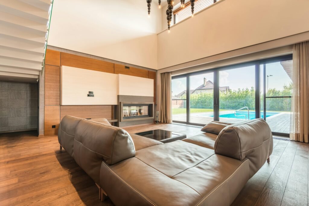 Spacious modern living room featuring a leather sofa and glass doors overlooking a swimming pool.