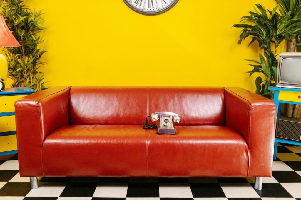 A vintage living room leather red couch, rotary phone, and vibrant decor