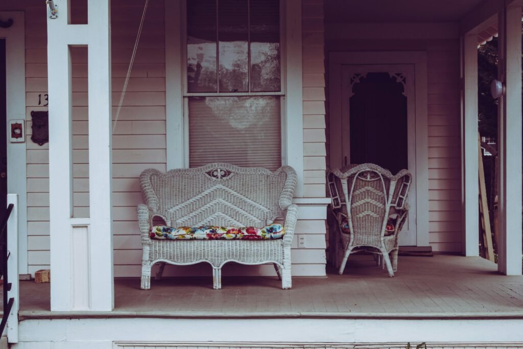 vintage-style front porch with white wicker chairs and floral cushions.